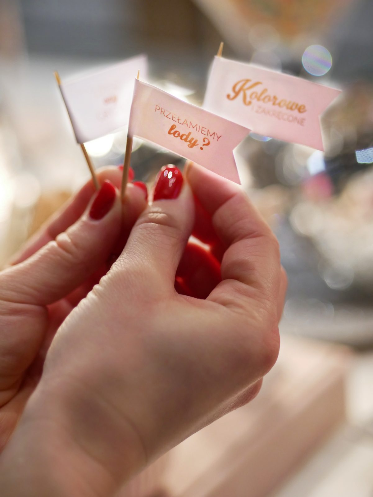 Paper flags in a hand at the Ice Dream gelateria reading "PRZEŁAMIEMY lody?" ("Shall we break the ice?", also literally "break the ice cream") and "Kolorowe i zakręcone" ("Colourful and swirled").