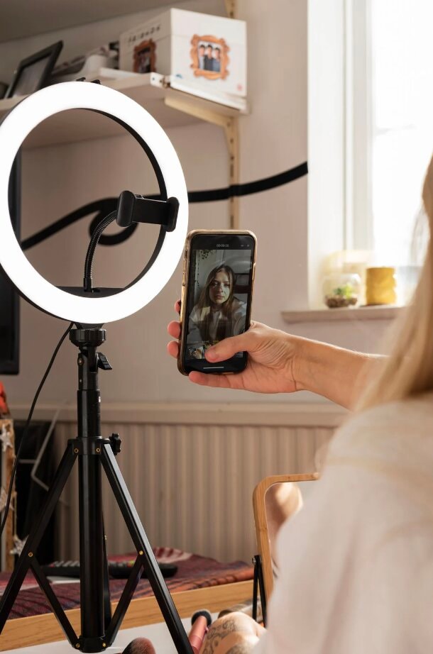 A recording setup with a ring light and a smartphone on a tripod during a shoot with an influencer